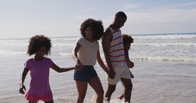 Smiling african american parents and their children walking and holding hands on the beach. family outdoor leisure time by the sea.