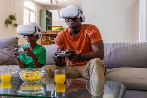 Father and son playing vr games on couch sharing joyful family bonding and entertainment
