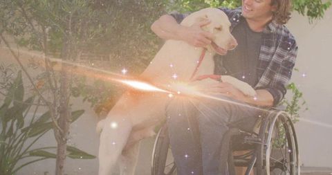 Man in wheelchair petting dog in sunlit garden showing mobility, friendship, therapy