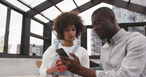 Diverse Couple Enjoying Coffee and Smartphone Time on Urban Roof Terrace