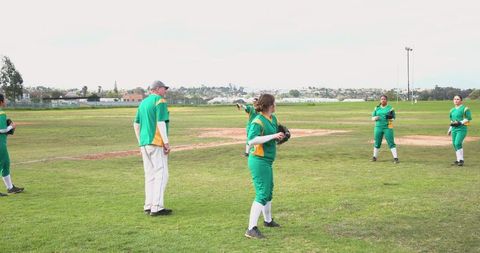 Female softball team practicing with coach in park