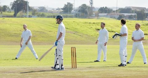 Cricket Players on Green Suburban Field Preparing Game Wickets