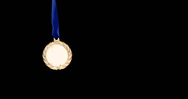 A gold medal hangs against a black background, with copy space. It symbolizes achievement and recognition in competitive events or other accomplishments.