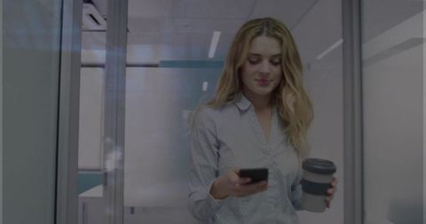 Modern Businesswoman Walking Through Office Corridor Holding Coffee and Smartphone