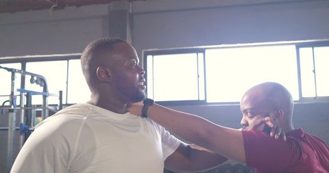 African men practicing self-defense drill in industrial gym with cable machine and weights