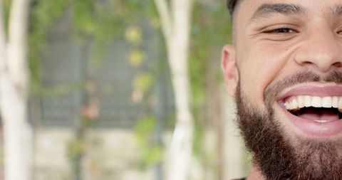Half-revealed bearded man laughing joyfully outdoors