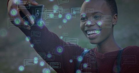 Joyful woman using smartphone relishing chat bubble interface outdoors