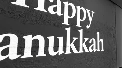 Dollying through textured corridor zooming on Happy Hanukkah projection and menorah closeup