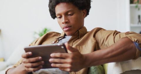 Young Man Relaxing at Home Using Tablet Device
