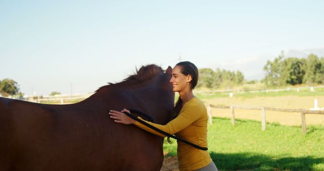 Young woman embracing brown horse in a sunlit pasture. Suitable for depicting themes of animal companionship, tranquility, and rural life. Can be used for promotional materials, advertisements, or blogs focused on equine activities, zen lifestyles, and nature retreats.