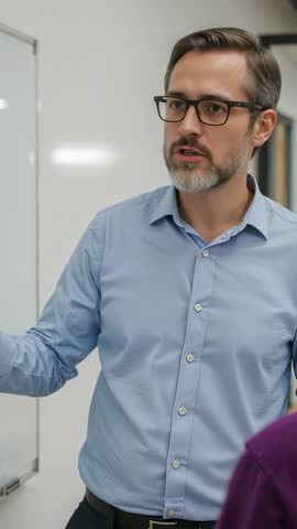 Vertical business training video: Instructor explaining strategy at whiteboard during meeting