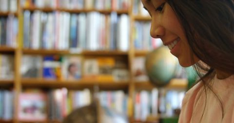 Smiling asian woman enjoying quiet moment in library
