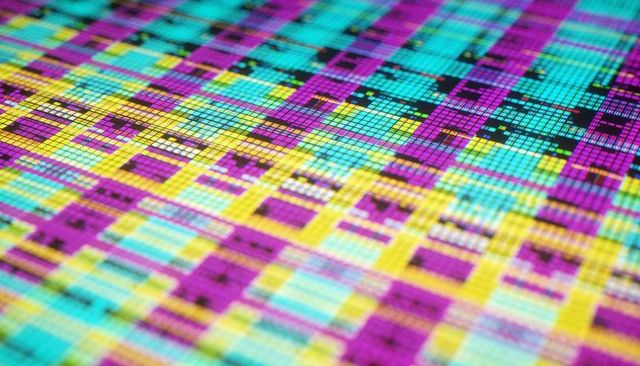 Silicon wafer revealing repeating die array with cyan magenta yellow grid and scribe lines