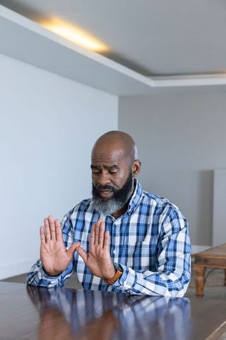 Senior Man Practicing Mindfulness Indoors Focusing with Raised Hands