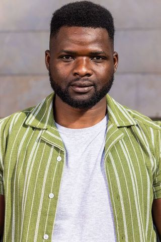 Confident african american man standing in green striped shirt urban portrait close-up