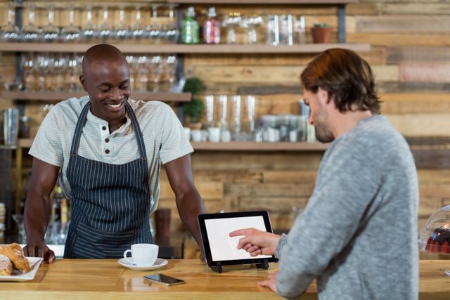 Man discussing over digital tablet with waiter in cafÃ©