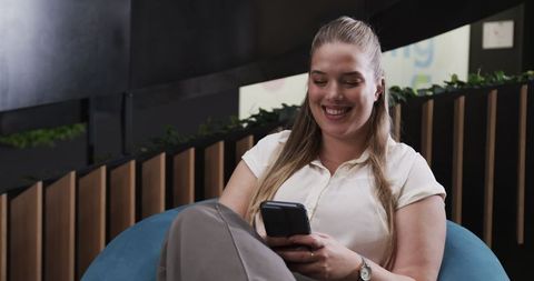 Businesswoman Relaxing and Engaging with Smartphone in Modern Office Lounge
