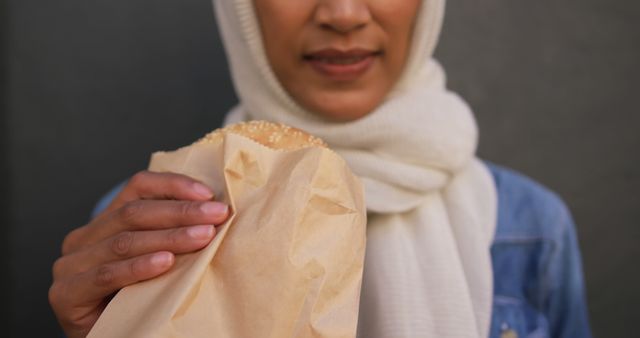 Woman Wearing White Hijab Holding Fast Food Paper Bag with Burger - Download Free Stock Images Pikwizard.com