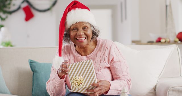 Happy senior african american woman wearing santa claus hat, having image call at christmas. Retirement, spending time at home and christmas concept.