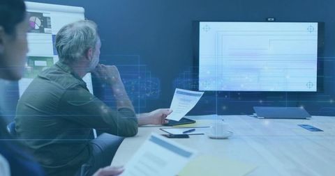 Mature professional reading report during digital strategy meeting with holographic display