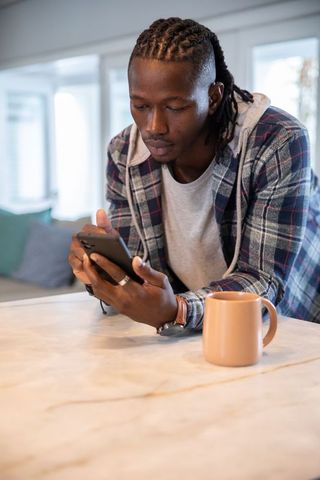 Relaxed man checking smartphone in bright modern kitchen