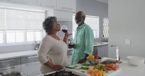 Senior Couple Enjoying Wine While Cooking Together in Modern Kitchen