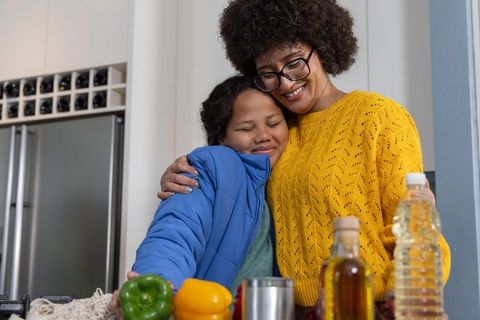 African american mother and daughter hugging in kitchen sharing warm family moment