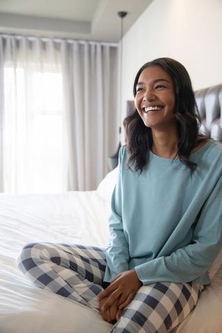 Smiling Woman in Cozy Bedroom on Comfortable Bed