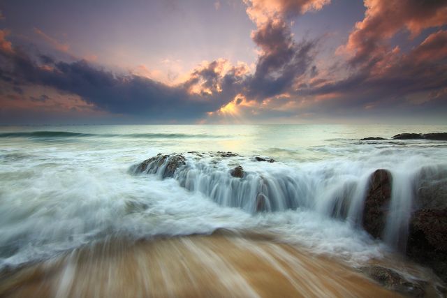 Serene Ocean Waves at Sunset with Dramatic Clouds and Coastline - Download Free Stock Photos Pikwizard.com