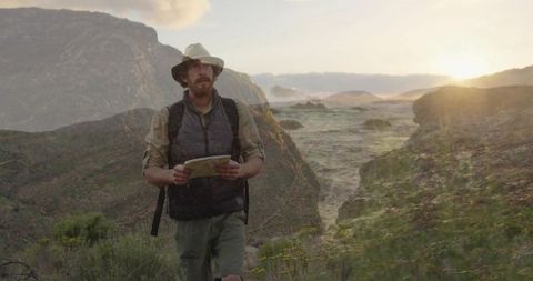 Hiker Exploring Canyon Trail at Sunset with Map and Backpack