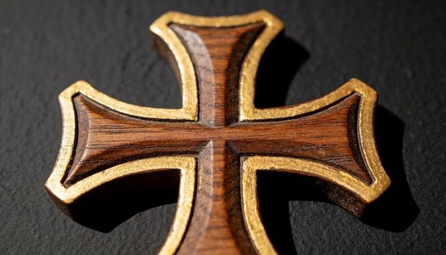 Gilded wooden cross closeup featuring carved grain, gold trim and dramatic shadow