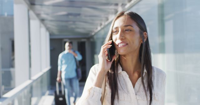 Image of happy biracial woman walking and using smartphone. business professionals and working in office concept.