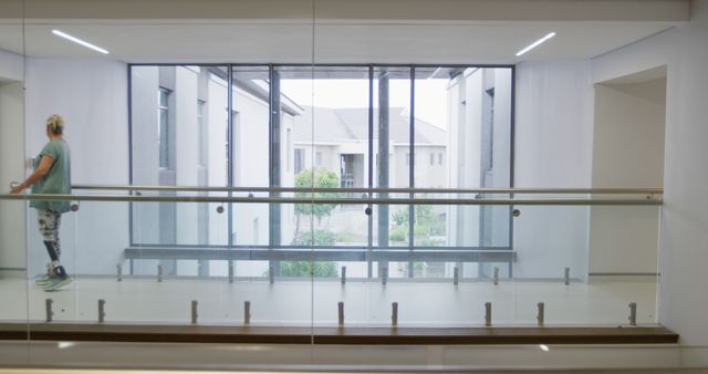 Person Walking through Modern, Bright Office Hallway with Glass Railings - Download Free Stock Images Pikwizard.com