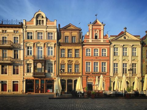 Sunlit colorful townhouses lining european market square with outdoor cafes at golden hour