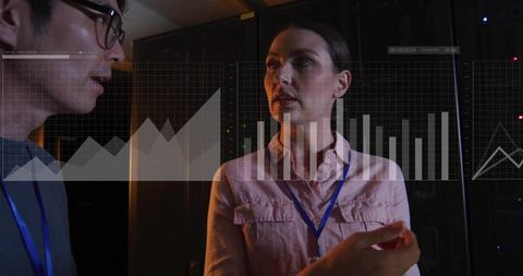 It engineers monitoring network performance in server room with data graph overlays