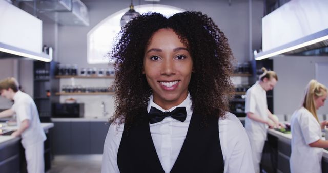 Portrait of happy diverse woman with bow tie in cook class in kitchen. Lifestyle, learning, food, cooking, unaltered.