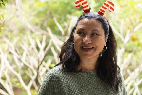 Hispanic woman in garden with festive candy cane headband