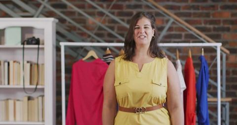 Smiling woman organizing clothing rack in fashion boutique