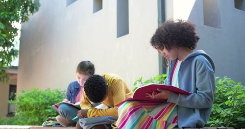 African American Teen and Diverse Classmates Studying Outdoors on Campus Courtyard Ledge
