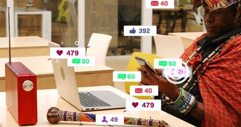 Senior gentleman wearing beaded wrap checking social media notifications in coworking