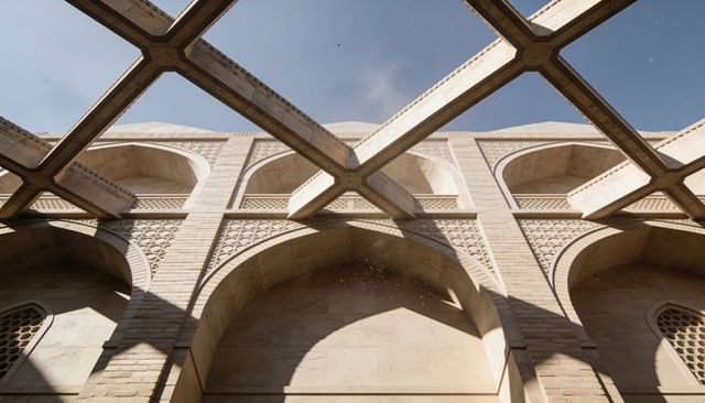 Sunlit islamic courtyard arcade with geometric jali lattice skylight casting dramatic shadows
