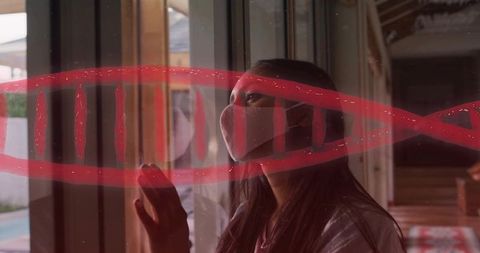 Woman wearing cloth mask pressing hand on glass with red painted symbol reflecting pool