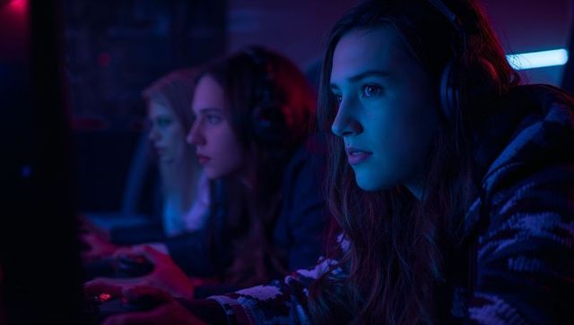 Focused Gamers Competing in Neon Lit Gaming Room