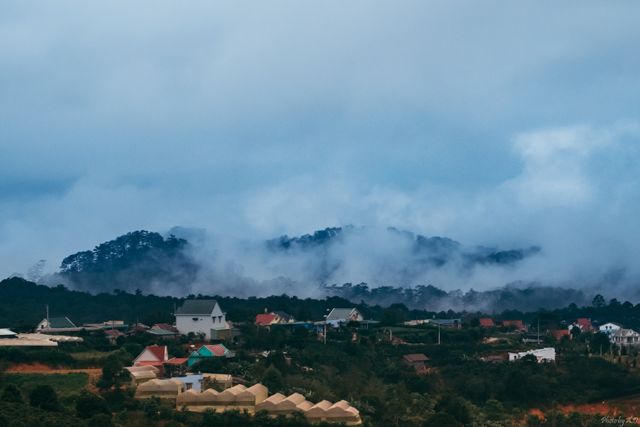 This image showcases a serene mountain village shrouded in mist and surrounded by foggy hills. Perfect for travel blogs, presentations on rural living, nature magazines, relaxation themes, and articles focusing on scenic landscapes.
