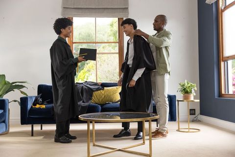 Diverse family preparing graduation gowns at home celebrating academic milestone