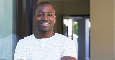 Confident Young Man Standing Near Window in Striped Shirt - Download Free Stock Images Pikwizard.com