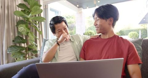 Father and Son Enjoy Leisure Time with Laptop at Home