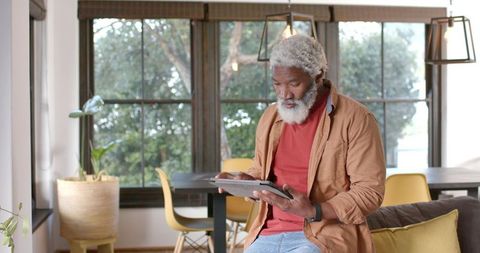 Senior Man Relaxing at Home with Tablet and Smartwatch