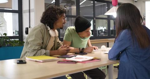 African american coworkers collaborating at shared workspace with notebooks and headphones