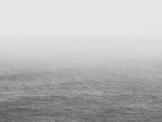 This image showcases a vast ocean under a grey, overcast sky. The nearly monochrome palette gives it a minimalist and serene quality. Suitable for themes like tranquility, simplicity, nature, and for backgrounds in digital projects or presentations.